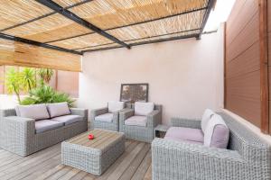 un patio al aire libre con muebles de mimbre y techo de madera. en Chambres d'Hotes Les Amandiers, en Saint-Tropez