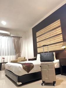 a hotel room with a bed and a suitcase at aresidencia sei putih in Medan