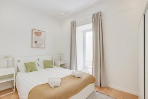 Un dormitorio blanco con una cama grande y una ventana en Vila Lopes, en Lisboa