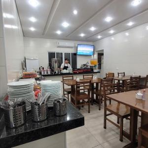 a restaurant with tables and a chef in the kitchen at Hotel Dona Lú in Sao Paulo