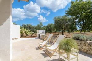 a patio with chairs and a table and a stone wall at Trullo Vicino al Mare in Ostuni