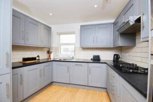 a kitchen with white cabinets and black counter tops at Spacious Bristol Apartment - Parking & WIFI in Bristol