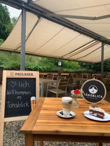 a wooden table with a piece of cake and a cup of coffee at Berggasthof Tönsblick in Oerlinghausen