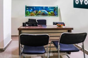 a desk with chairs and an aquarium on the wall at Hotel O Dsr Residency Near Nexus Hyderabad in Hyderabad