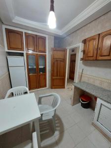 una cocina con armarios de madera y una mesa y sillas blancas. en Appartement S2 Kantaoui vue mer, en Port El Kantaoui
