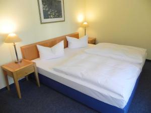 um quarto com uma cama grande com lençóis brancos e almofadas em Ferienwohnung 1 2 15 Inselstrand em Ahlbeck