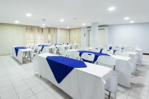 una habitación con mesas blancas y sillas con mesas azules en Apartotel Tairona, en San Pedro
