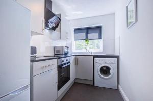a white kitchen with a washing machine and a window at Spacious 2 Bedroom Apartment in London