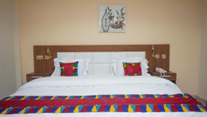 sypialnia z dużym białym łóżkiem z kolorowymi poduszkami w obiekcie RHOGEM Hotel w mieście Sekondi-Takoradi
