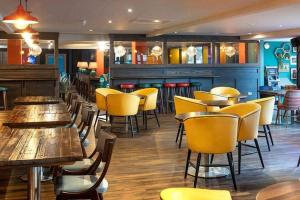 un restaurante con mesas de madera y sillas amarillas en The Hudson @ Silversands, en Lossiemouth