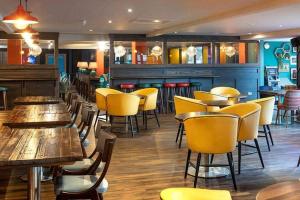 a restaurant with wooden tables and yellow chairs at The Hudson @ Silversands in Lossiemouth