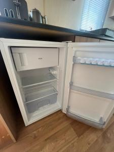 an empty refrigerator with its door open in a kitchen at 3 Bedroom Caravan, Sleeps 8 Lyons Lido Beach in Prestatyn