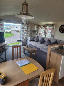 a living room with a couch and a table at Arual Caravan Manor House Park. Allonby, Cumbria in Maryport