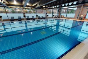 a large swimming pool with blue tiles in a building at Village Hotel Edinburgh in Edinburgh