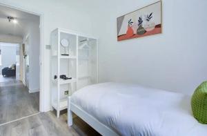 a white bedroom with a bed and a white shelf at Spacious 2 Bedroom Apartment in London
