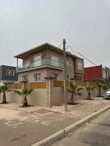 une maison dans une rue bordée de palmiers dans l'établissement Spacieuse villa familiale avec piscine Founty, à Agadir