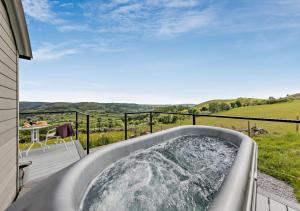 a hot tub on the balcony of a house at Cwt Eithin in Llangadfan