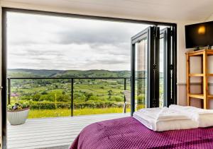 a bedroom with a bed and a balcony with a view at Cwt Eithin in Llangadfan