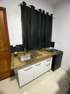 a kitchen with a sink and a black shower curtain at Pousada Brunetti in Penha