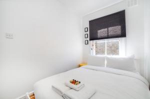 a white bedroom with a white bed and a window at Amazing 2BDR apt near park, Herne Hill in London