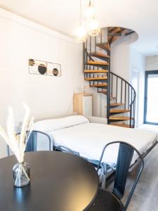 a room with two beds and a table and a spiral staircase at VUT Adarve in Avila