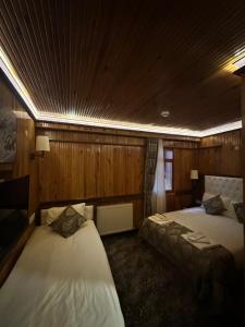 a bedroom with two beds in a room with wooden walls at Ayder Hasimoglu Hotel in Ayder Yaylasi