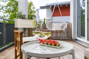 two glasses of wine and a plate of fruit on a table at Blueberry Living - Design Loft nahe München - Dachterrasse - S-Bahn in Gauting