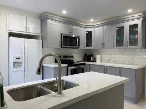 a white kitchen with a sink and a refrigerator at LuxuryCottage KingBed PrivateYard BBQ Deck Gazebo in Niagara Falls