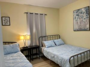 une chambre avec deux lits et une table avec une lampe dans l'établissement Victoria Family Vacation Home - King Bed Private Yard BBQ Deck Gazebo - 4 Minutes To The Falls, à Niagara Falls