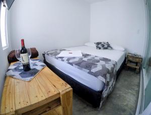 1 dormitorio con 1 cama y 1 botella de vino en la mesa en Hotel & Rooftop Farallones, en Betania