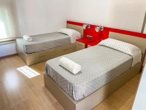 2 bedden in een kleine kamer met rode accenten bij Leevin Student Barcelona in Barcelona