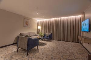 skyline Hotel & Suites في تبوك: غرفة معيشة مع أريكة وتلفزيون وكراسي