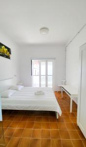 a white bedroom with a bed and a window at Las Eras Nest Hostel in Las Eras