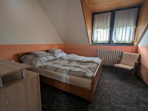 um quarto com uma cama, uma cadeira e uma janela em Várkapitány-lak em Csesznek