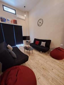 a living room with a couch and a clock on the wall at Duplex guest house in Batroun in Batroûn