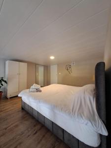 un grande letto bianco in una camera con pavimenti in legno di Duplex guest house in Batroun a Batroûn