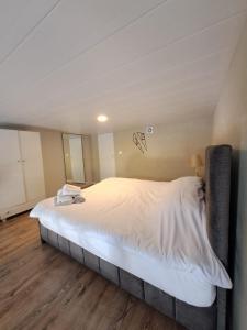 Duplex guest house in Batroun في البترون: سرير أبيض كبير في غرفة ذات أرضيات خشبية