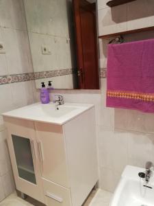 baño con lavabo blanco y toalla púrpura en Casa Güelito, en Candás