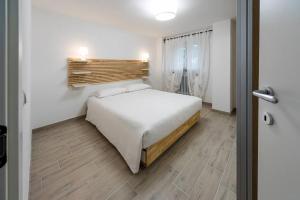 a bedroom with a white bed and a wooden floor at Villa de Riseis B&B in Pescara