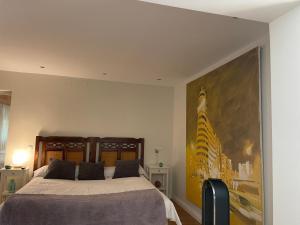 a bedroom with a bed with a large painting on the wall at Espléndido dormitorio en Suite in Fuente el Saz
