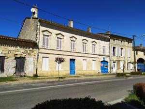 an old white building with blue doors on a street at Céline et José in Cubzac-les-Ponts