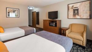 um quarto de hotel com duas camas e uma televisão e uma cadeira em Best Western Westminster Hotel em Westminster