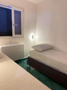 una camera con due letti e una finestra con persiane di 2 bedrooms bungalow at Marina di Camerota 60 m away from the beach with enclosed garden and wifi a Marina di Camerota