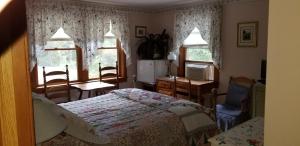 a bedroom with a bed and two windows at Eastgate Inn B&B in Lenox