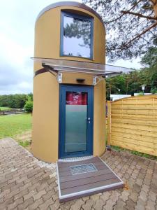 una pequeña casa con una puerta azul y una valla en Tiny House Ückeritz, en Ückeritz