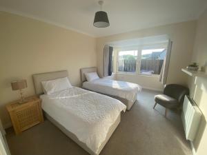 a bedroom with two beds and a chair and a window at The Lodge at Woodend in Kemnay