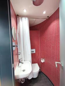 W wyłożonej czerwonymi kafelkami łazience znajduje się toaleta i umywalka. w obiekcie Tiny House Ückeritz w mieście Ückeritz