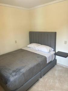 um quarto com uma cama com uma cabeceira cinzenta em San Marcos Envigado Medellin em Envigado