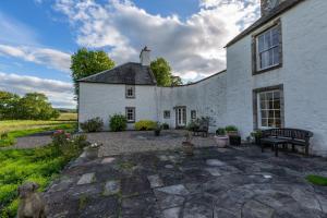 a white building with a bench in front of it at Airds of Kells House in Castle Douglas