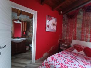 ein Schlafzimmer mit einer roten Wand mit einem Bett und einem Waschbecken in der Unterkunft The Queen in Giannetti